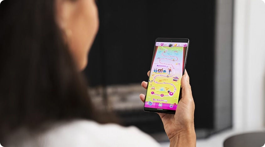 Woman holding a smartphone open to Candy Crush Saga