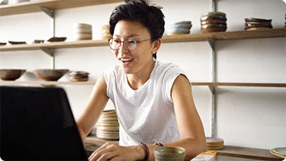 A person using a laptop indoors and smiling.