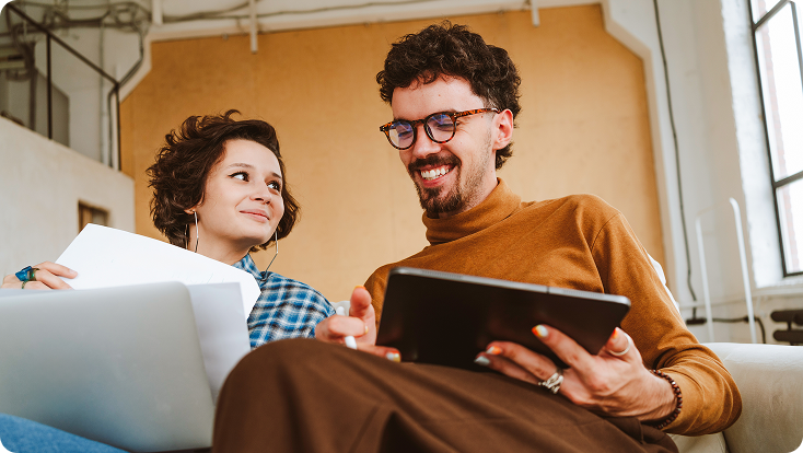  Two people working together, reviewing documents on a laptop and tablet.