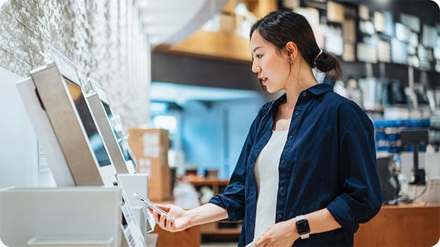 A person making a transaction at a digital terminal using a cellphone in a store.