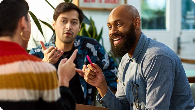 Three people talking to each other and smiling.