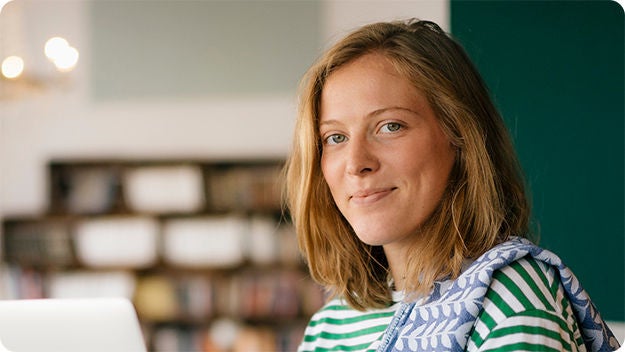 Two people sitting at a desk, one person in smiling at the other.