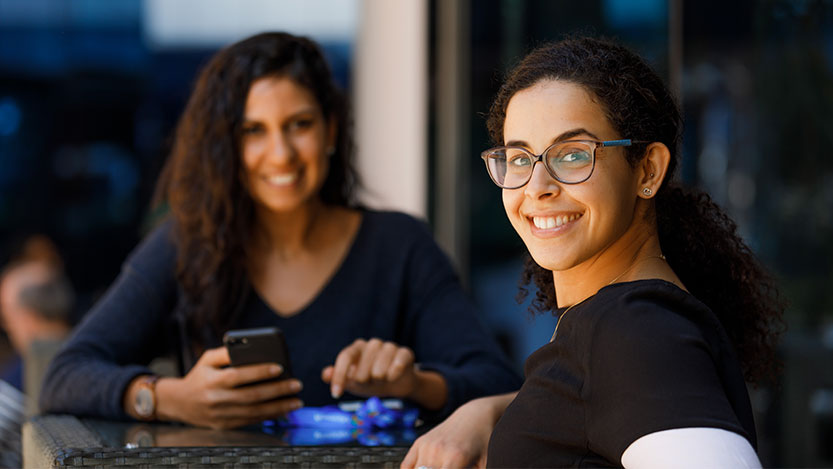 Two people sitting at a table and smiling at the camera.