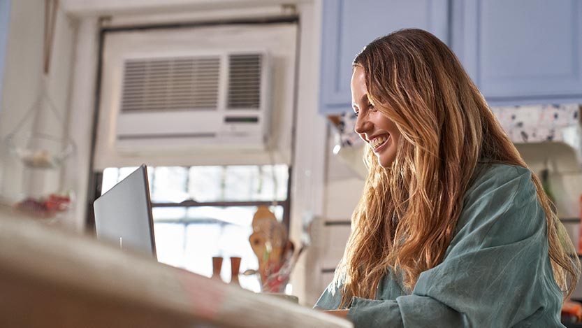 A woman is sitting at a table and working on a laptop computer.