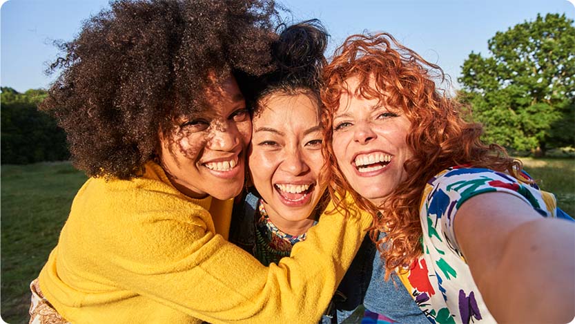 Three people hugging while looking at the camera.