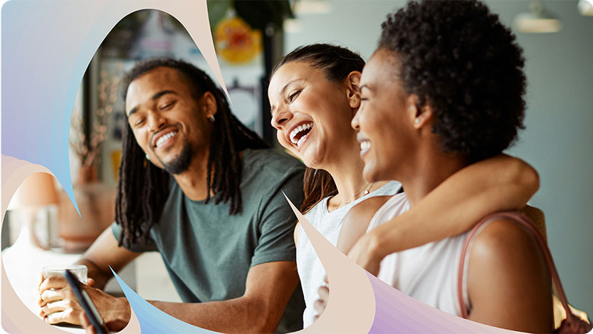 Three people laughing and looking at a cell phone.