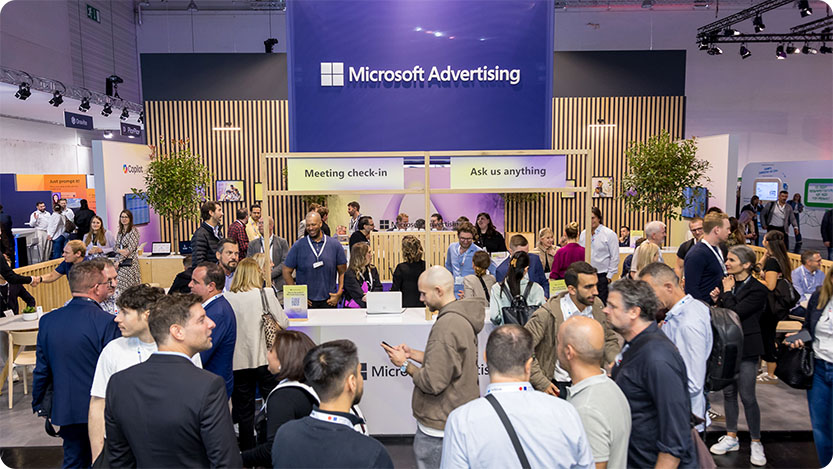 A crowd gathers at the Microsoft Advertising booth at DMEXCO 2025, engaging with staff at the “Meeting check-in” and “Ask us anything” counters.