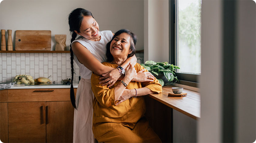 Two people in a kitchen hugging and smiling.